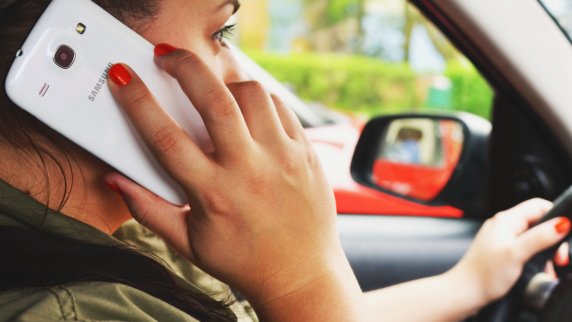 Frau mit Smartphone am Steuer