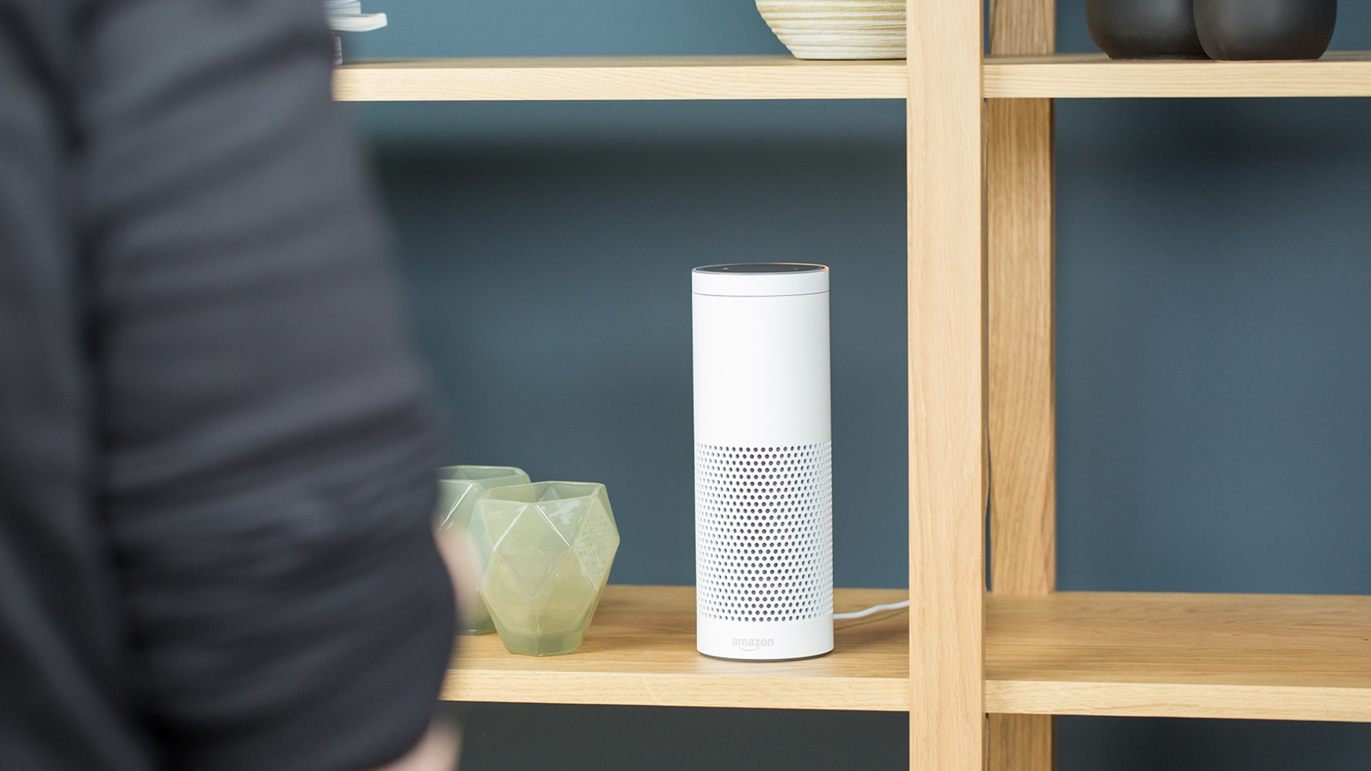 Amazon Echo Frau steht vor Regal in dem Amazon Echo steht