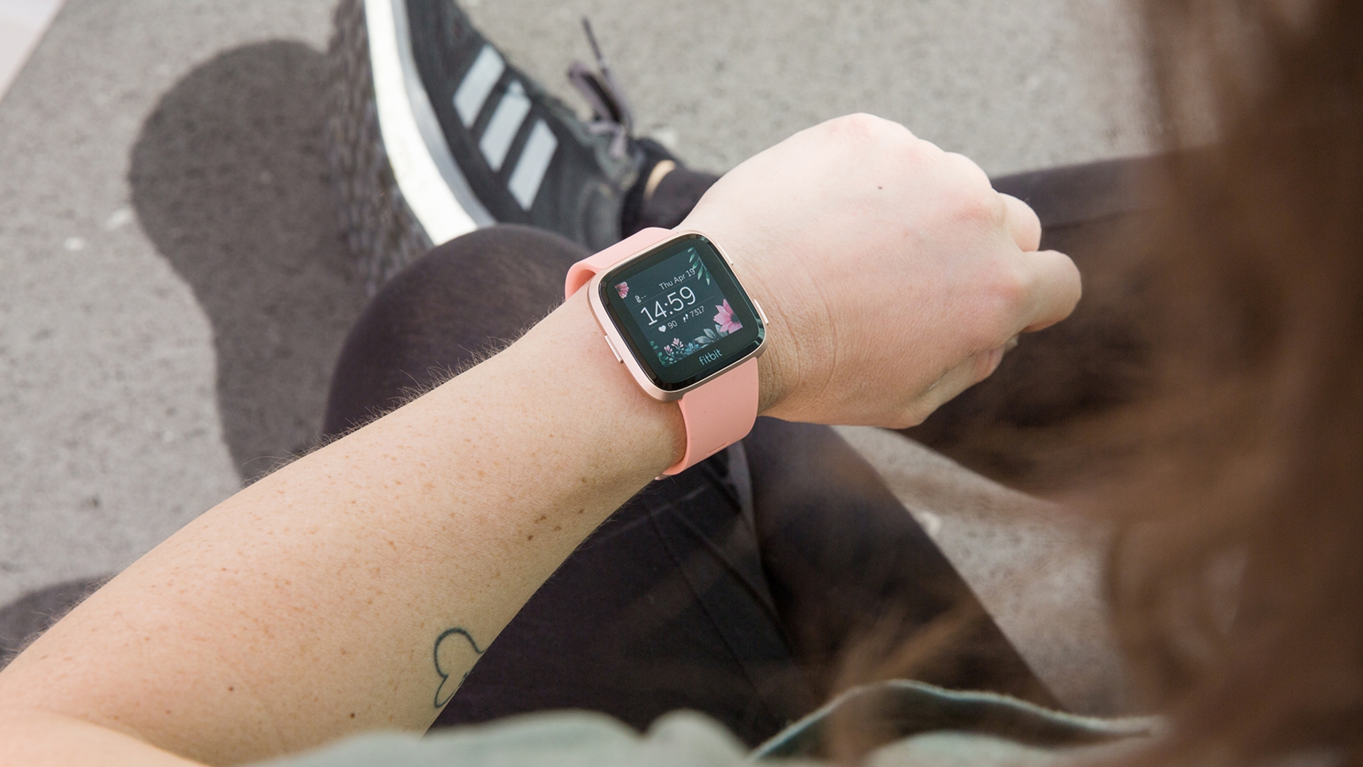 Fitbit Versa Fitbit Versa Frau schaut auf Smartwatch