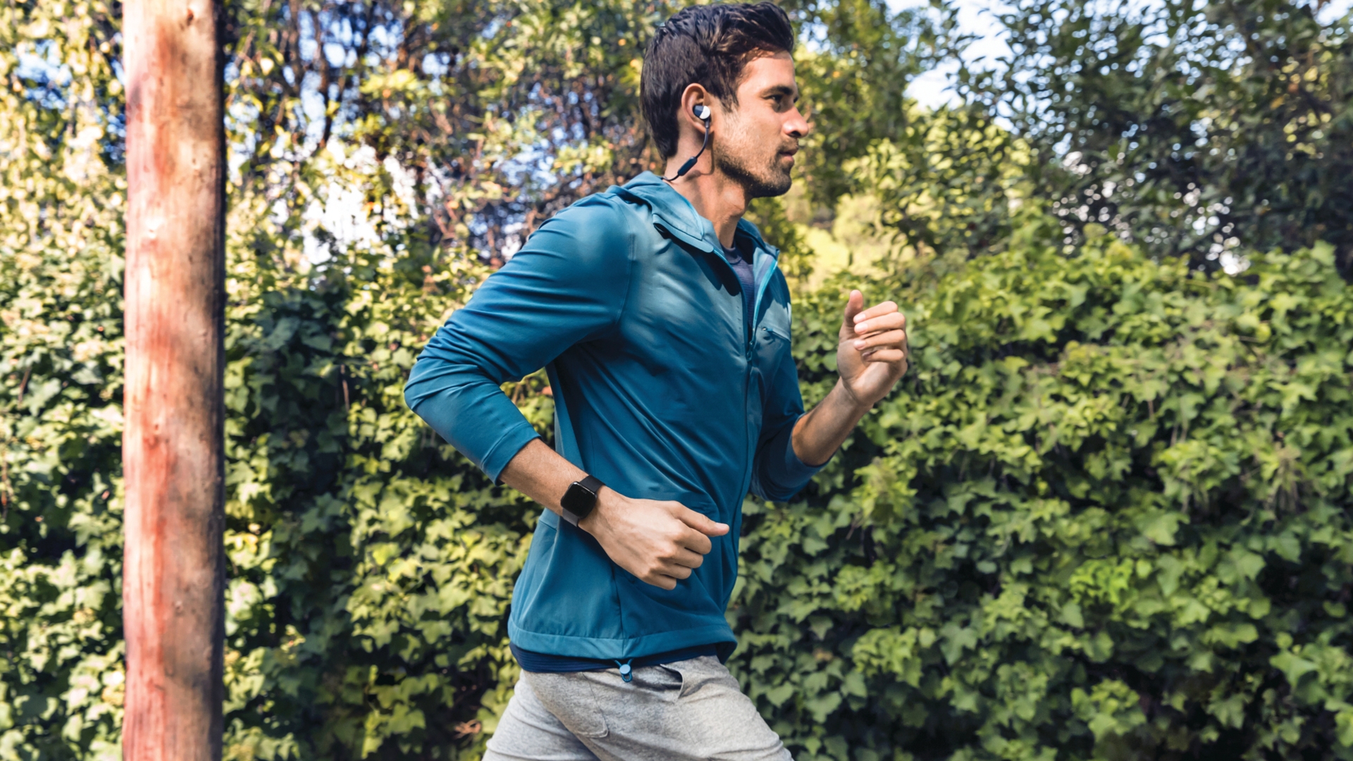 Fitbit Versa, Fitness-Tracker, Wearable Joggen, Sport, Kopfhörer Mann joggt im Wald
