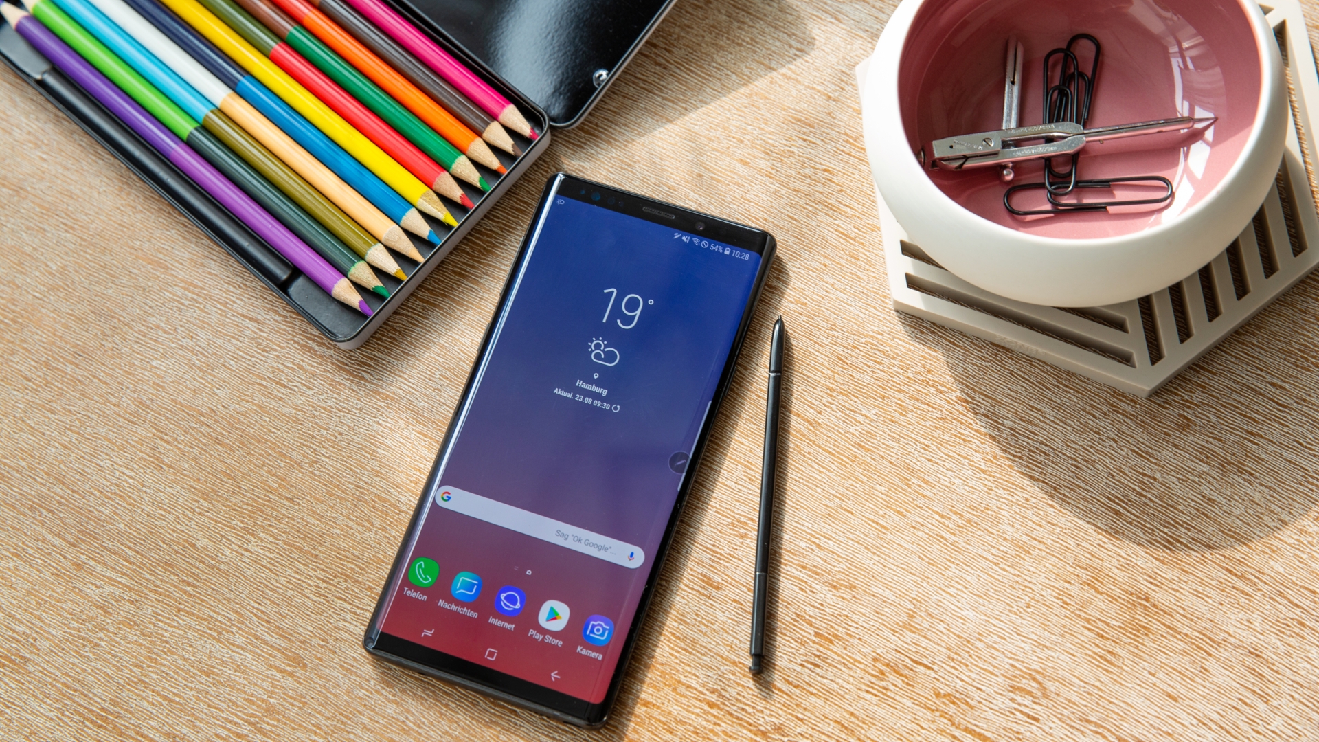 Samsung Galaxy Note 9 Galaxy Note 9 auf einem Schreibtisch neben einem Kasten voller Buntstifte.