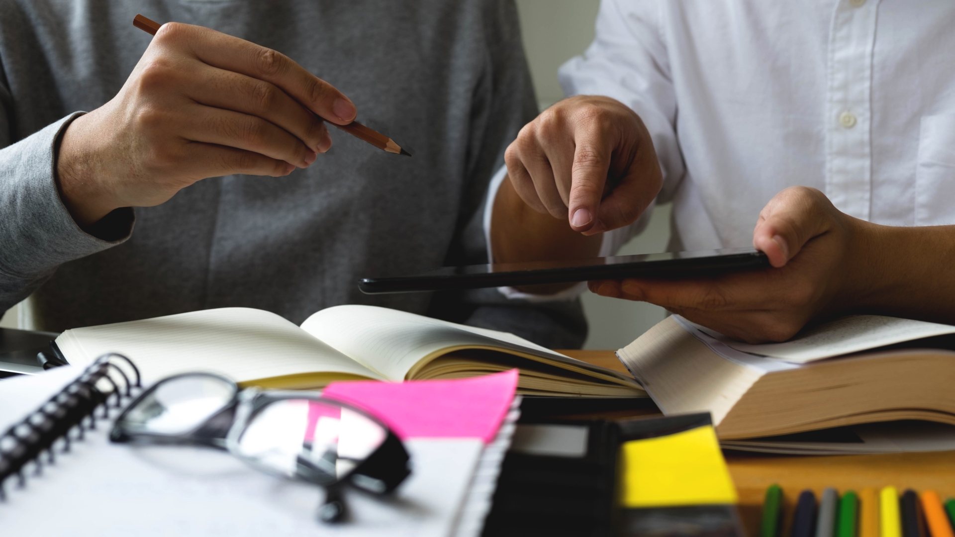 Tablet, Studenten, Lernen, Universität Bücher auf einem Tisch, Hände die ein Tablet halten, Oberkörper im Hintergrund