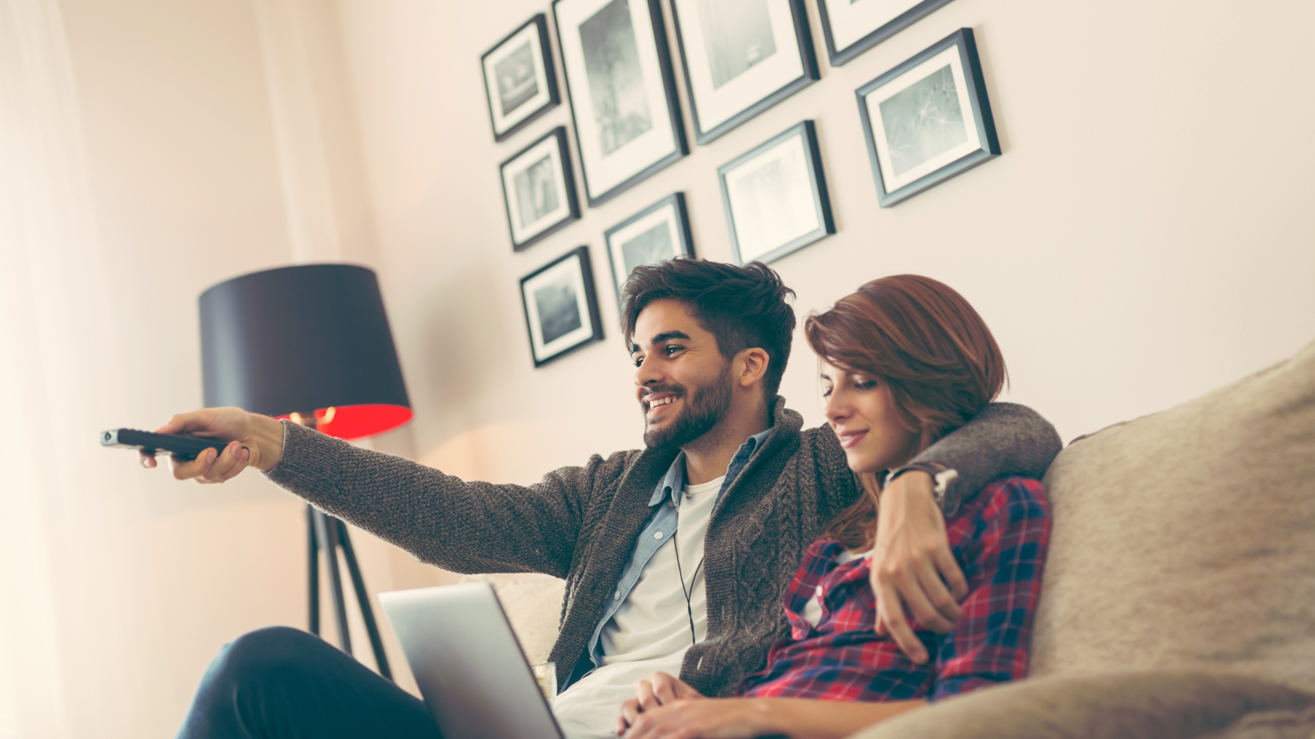 fernsehen, sky, tv, sofa, laptop Kuschelndes Pärchen auf der Couch mit der Fernbedienung in der Hand