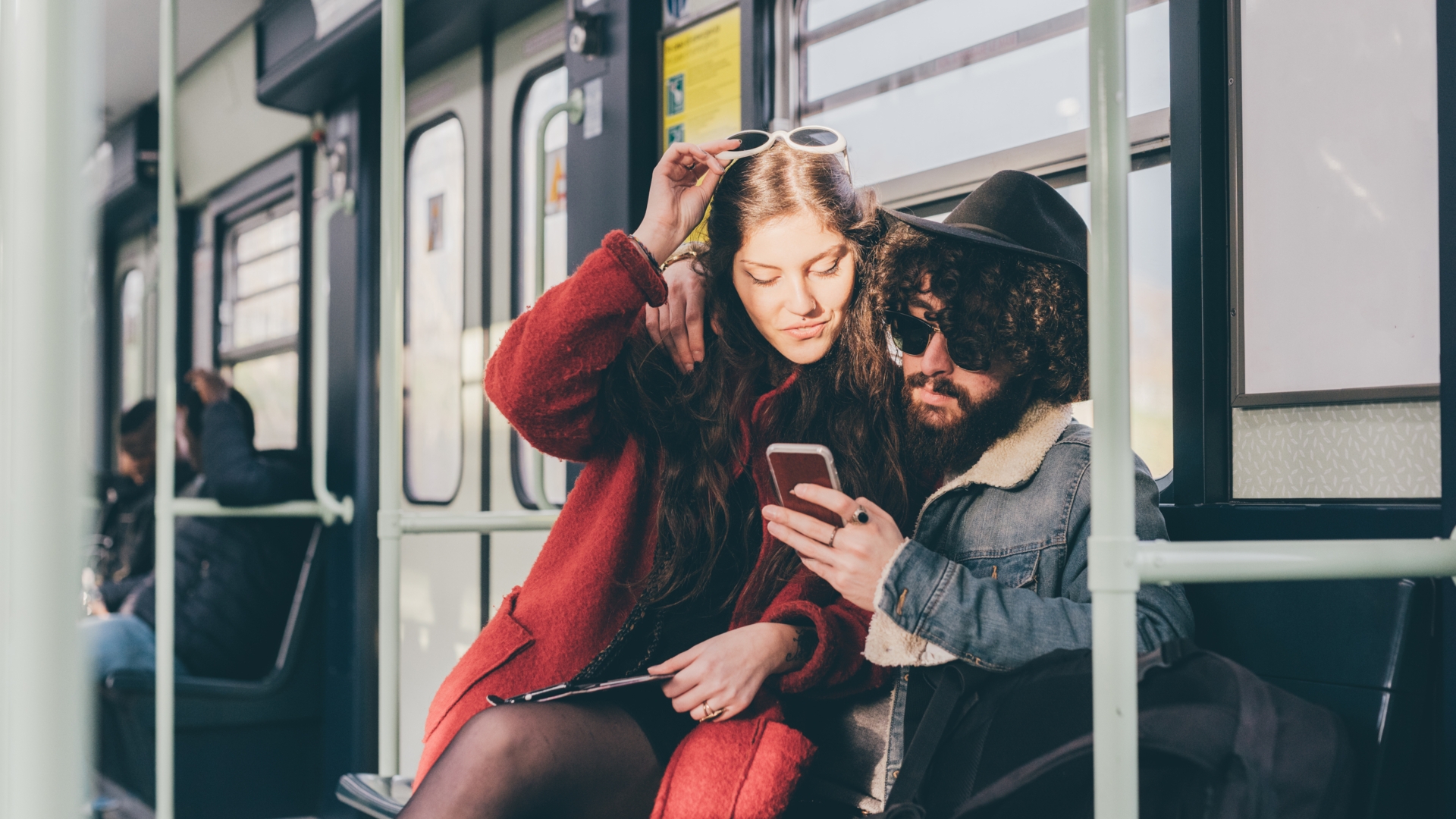 Young couple sitting on subway train, looking at smartphone Young couple sitting on subway train, looking at smartphone