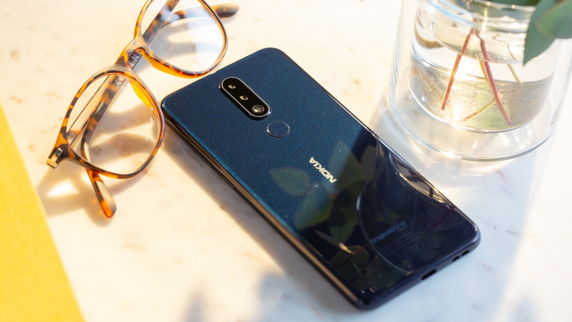 Nokia 5.1 Plus Das Nokia 5.1 Plus liegt auf einem Tisch neben einer Brille.