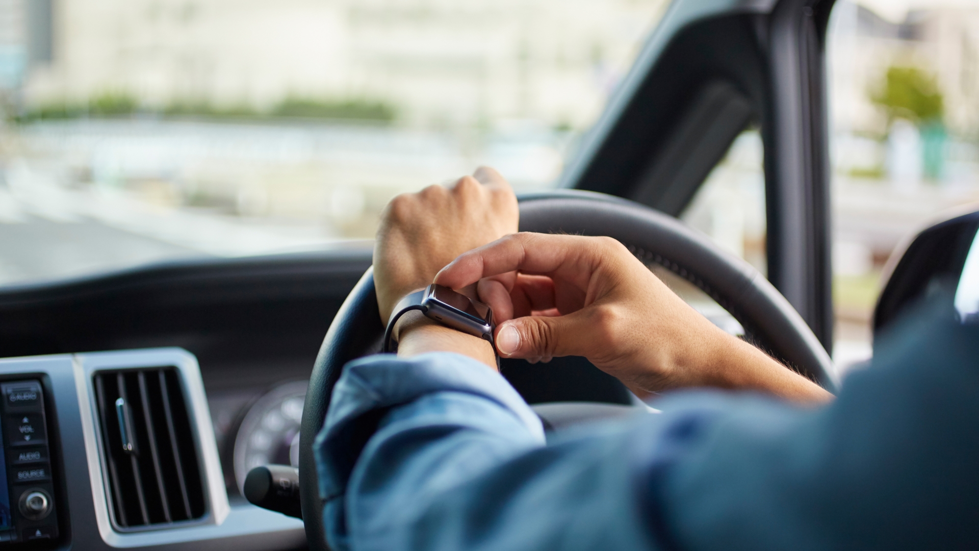 Autofahrer betätigt Smartwatch am Steuer.