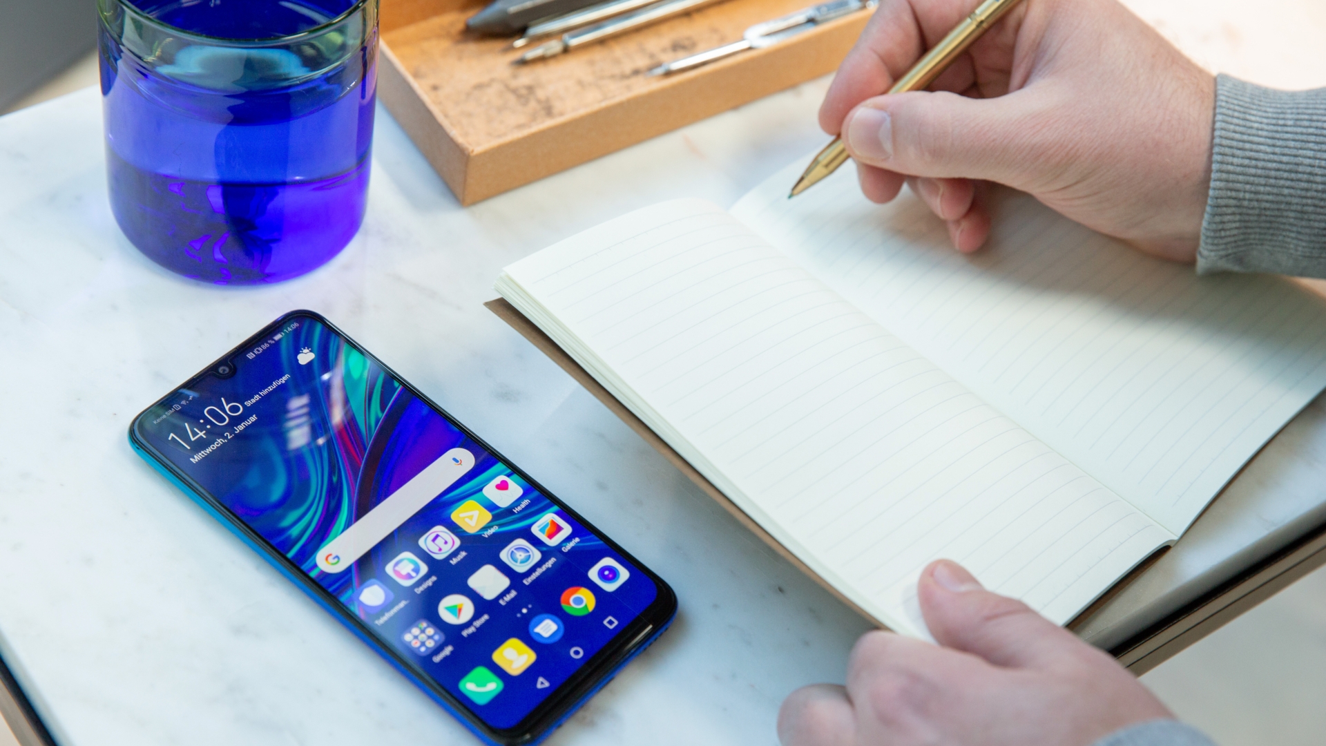 Huawei P Smart 2019 Smartphone liegt neben Notizbuch in dem geschrieben wird.