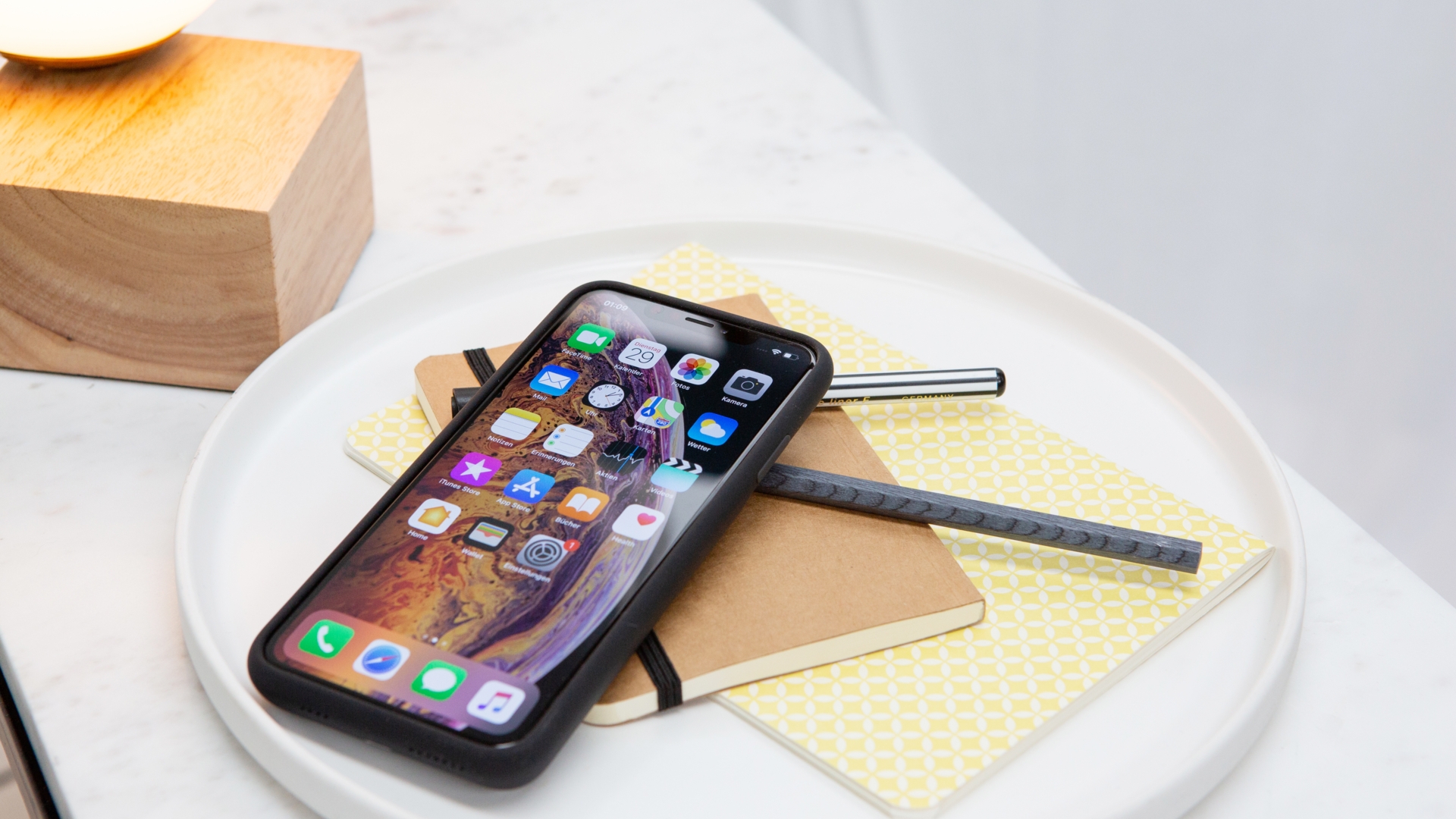 iPhone Xs Max Smart Battery Case Ein iPhone in einer Akkuhülle liegt auf einem Schreibtisch.