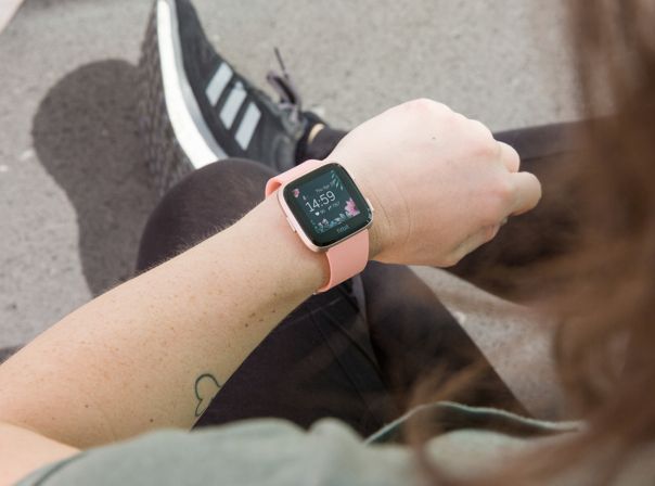 Fitbit Versa Fitbit Versa Frau schaut auf Smartwatch