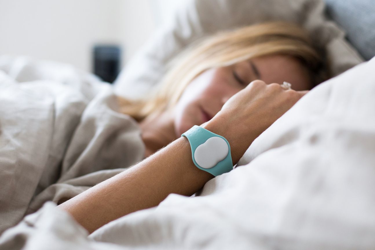 Schlafende blonde Frau mit Ava am Handgelenk.