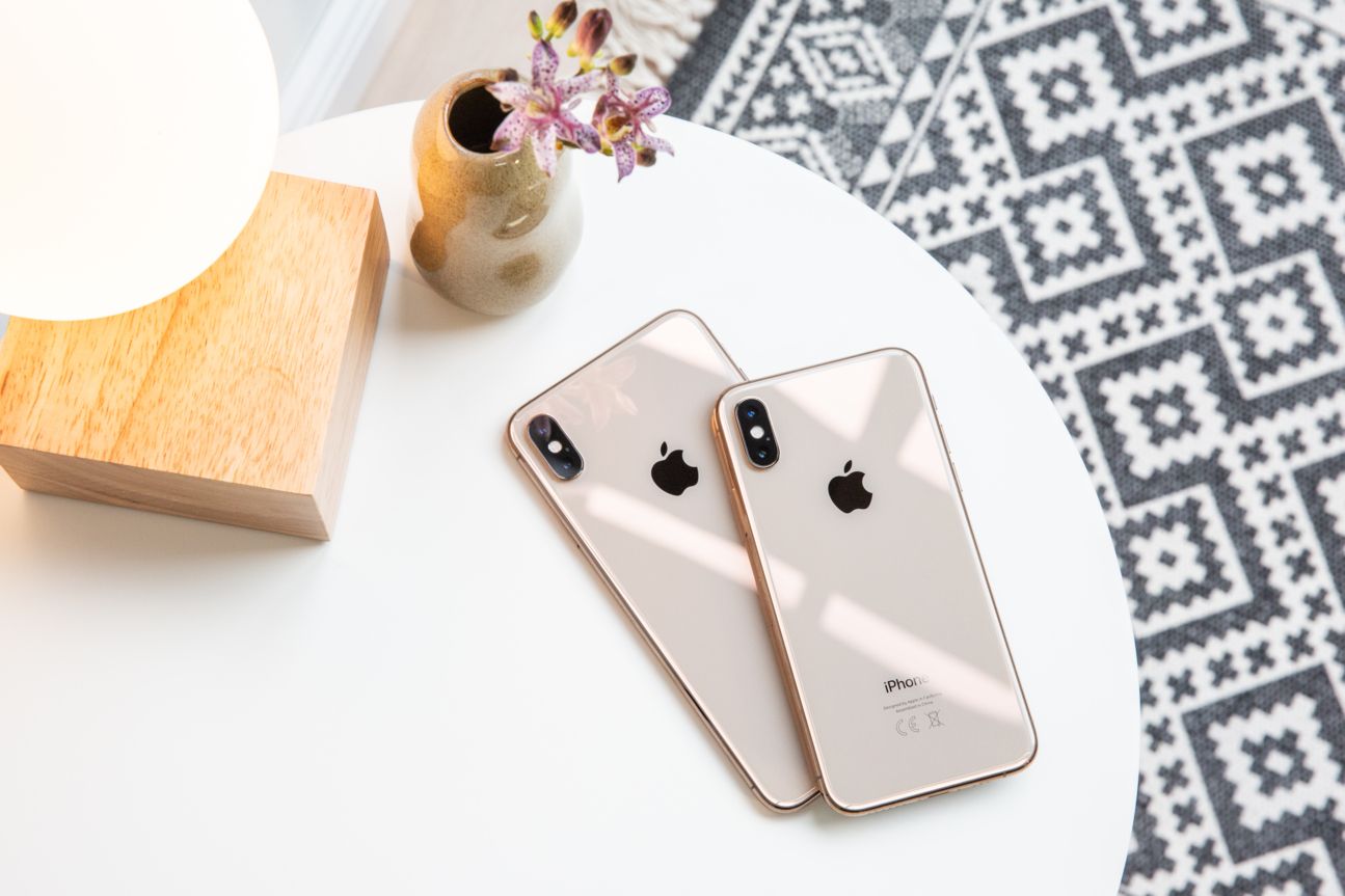 Apple iPhone Xs und Xs Max Die Rückseiten vom iPhone Xs und Xs Max auf einem Kaffeetisch mit Blümchen.
