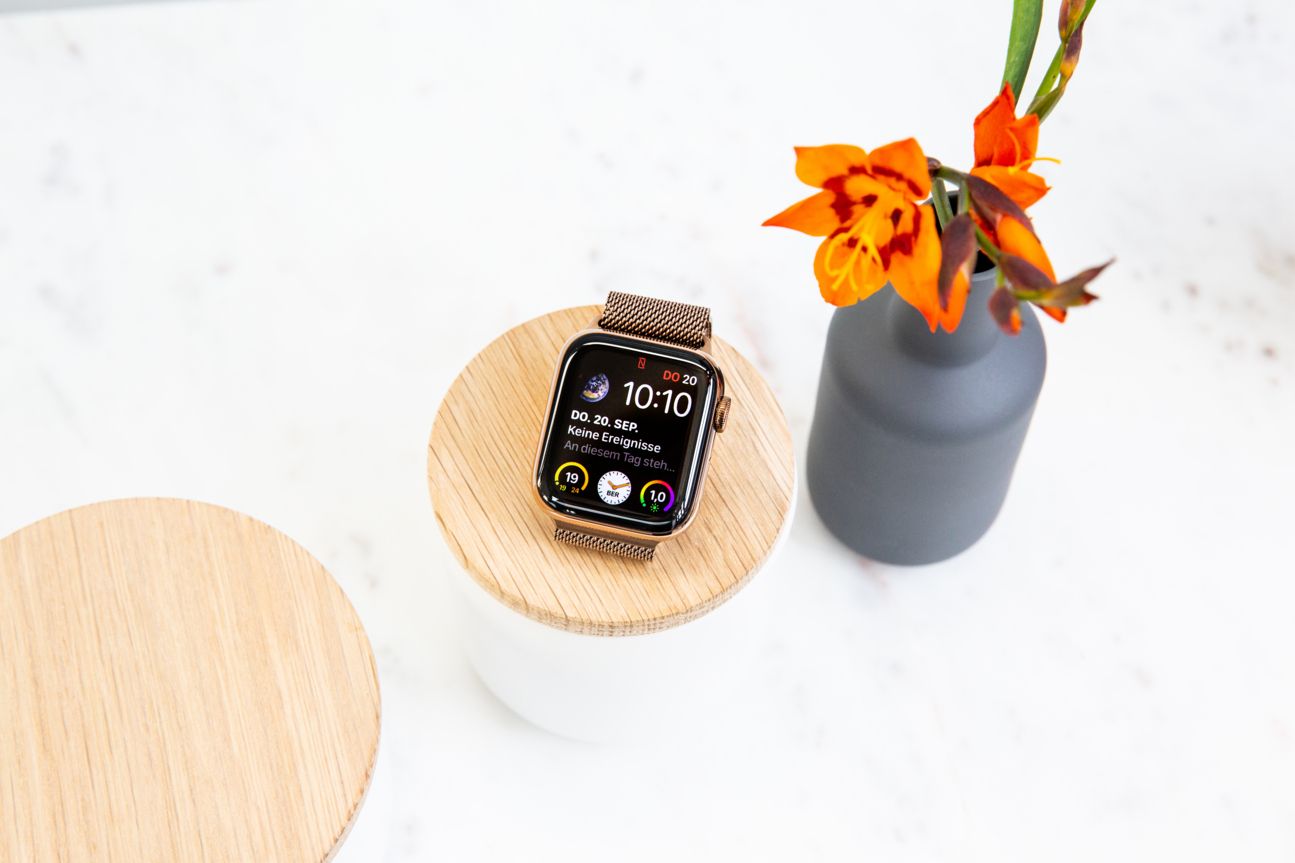 Die Apple Watch Series 4 auf einem Holzpodest neben einer Pflanze.