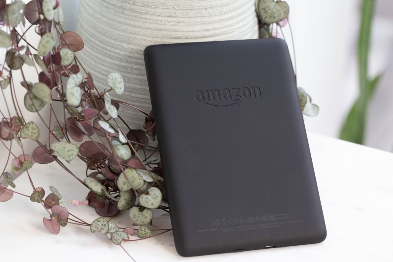 Amazon Kindle Paperwhite Der Kindle Paperwhite lehnt auf einem Schreibtisch an einem Deko-Gegenstand.