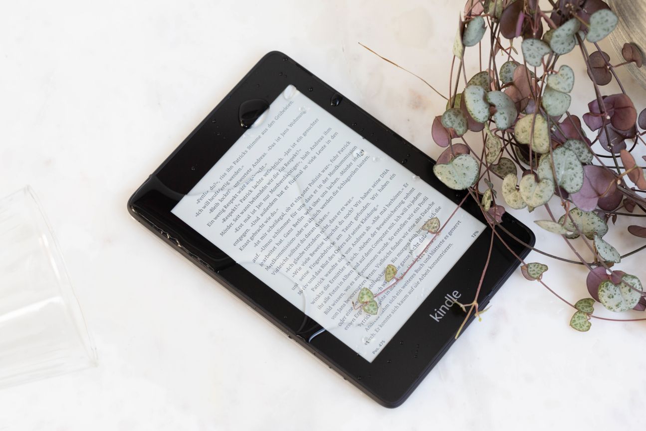 Amazon Kindle Paperwhite Der Kindle Paperwhite liegt auf einem Tisch neben einem Deko-Gegenstand.