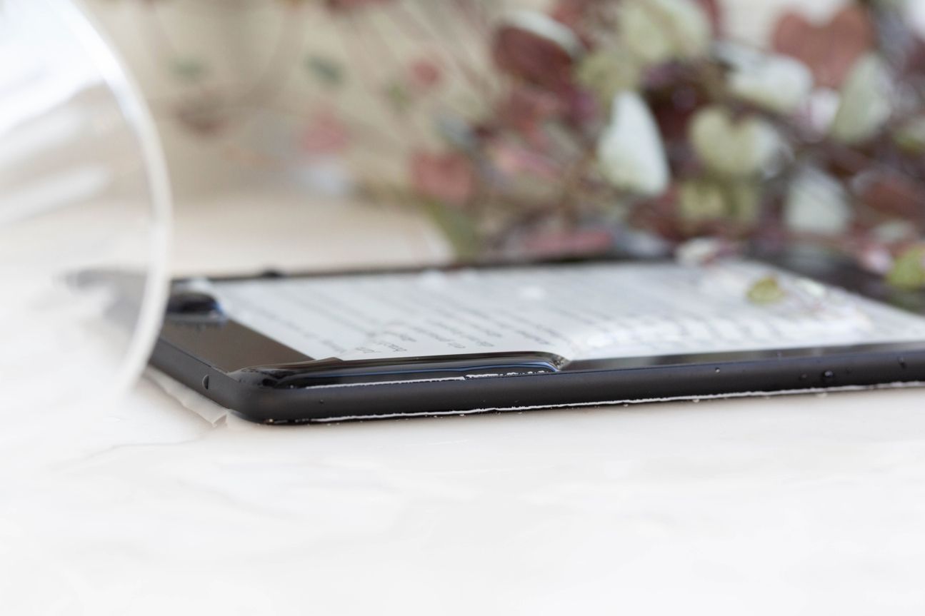 Amazon Kindle Paperwhite Der Kindle Paperwhite liegt auf einem Tisch, im Hintergrund steht ein Deko-Gegenstand.