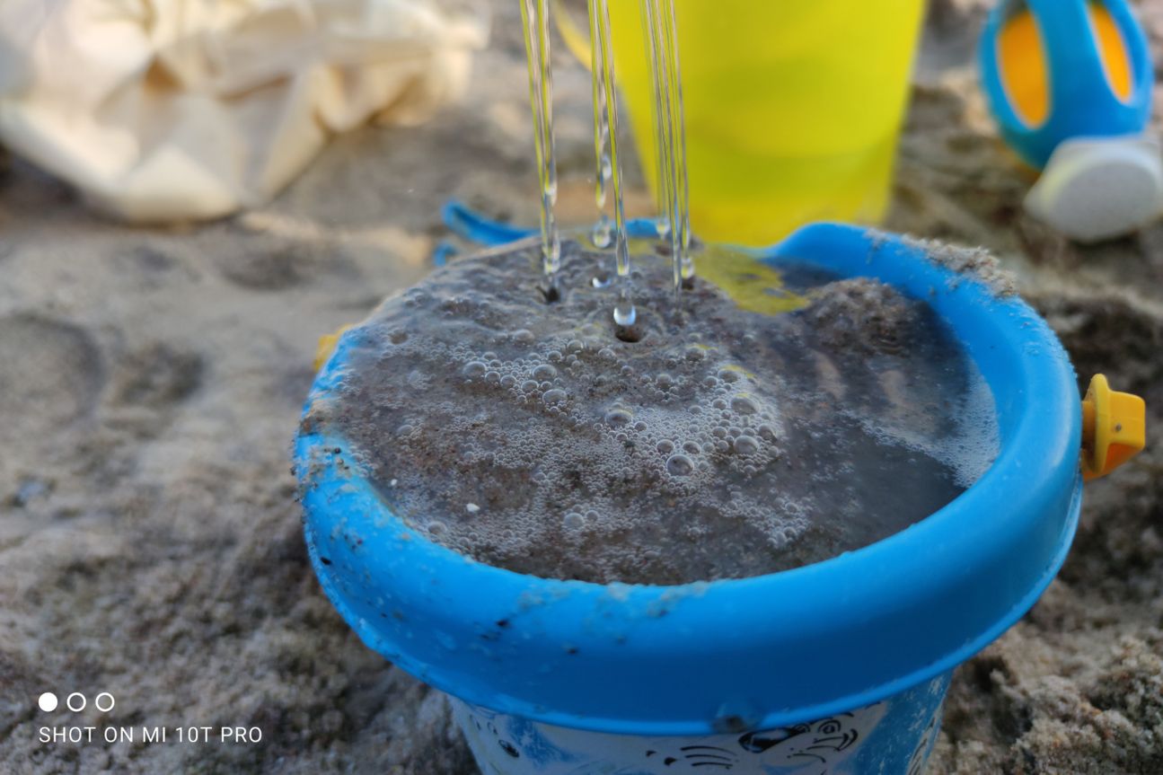 Foto zeigt Sandspielzeug und Wasser am Strand