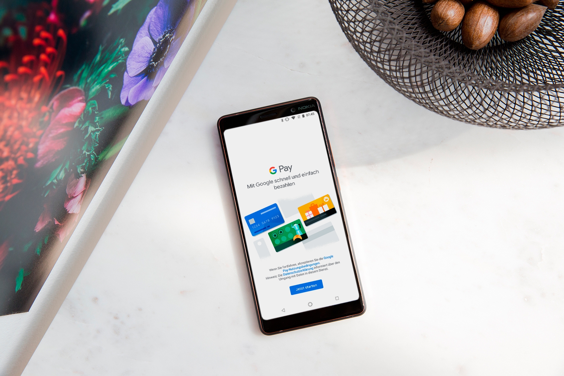 Smartphone mit geöffneter "Google Pay"-App auf einem weißen Tisch.