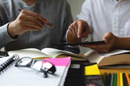 Tablet, Studenten, Lernen, Universität Bücher auf einem Tisch, Hände die ein Tablet halten, Oberkörper im Hintergrund